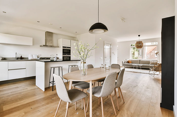 Fotografia interna de um imóvel, mostrando o conjunto de jantar em uma sala com chão de madeira