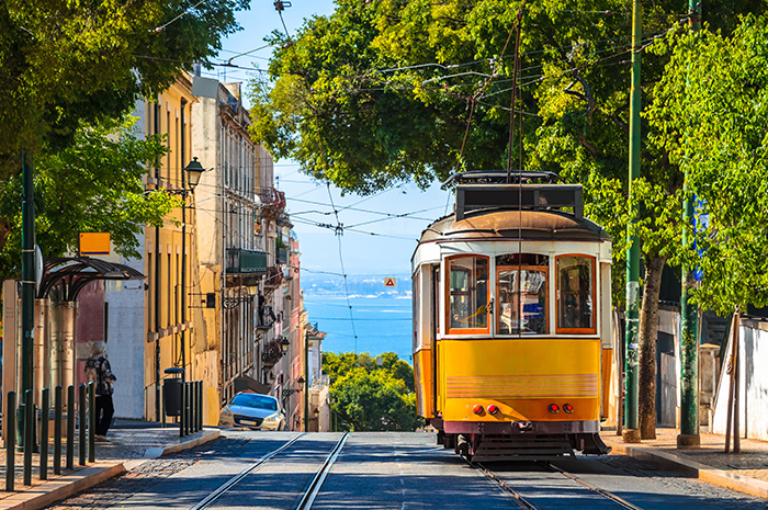 Fotografia mostrando uma rua em Portugal, com destaque para um bonde amarelo.
